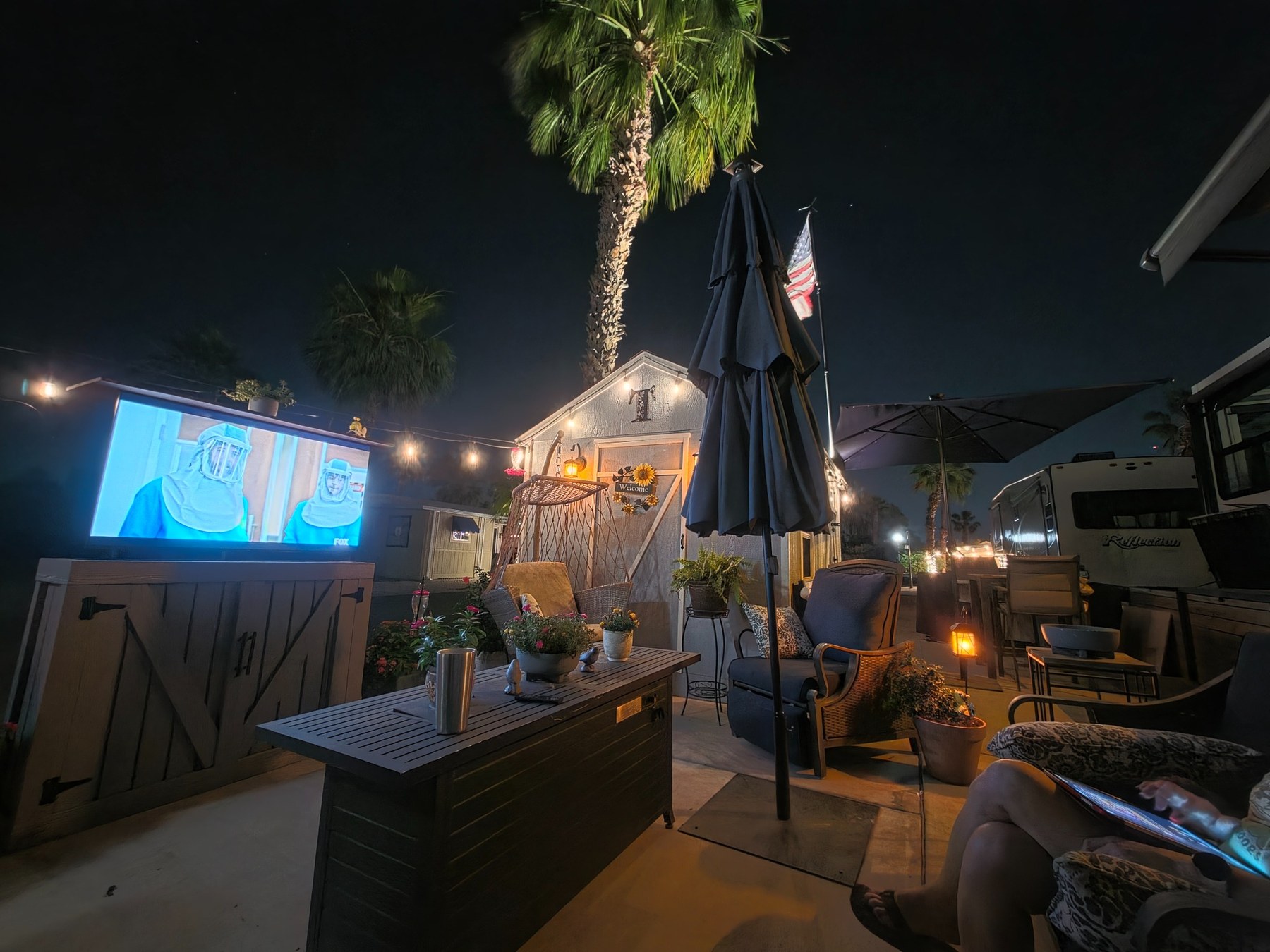 Nighttime outdoor TV cabinet and seating area